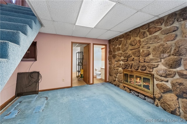 unfurnished living room featuring carpet floors, a fireplace, and a drop ceiling