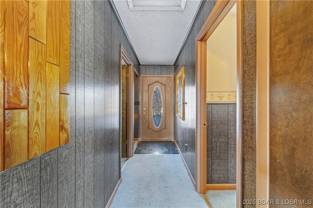 corridor featuring a textured ceiling, carpet flooring, and baseboards