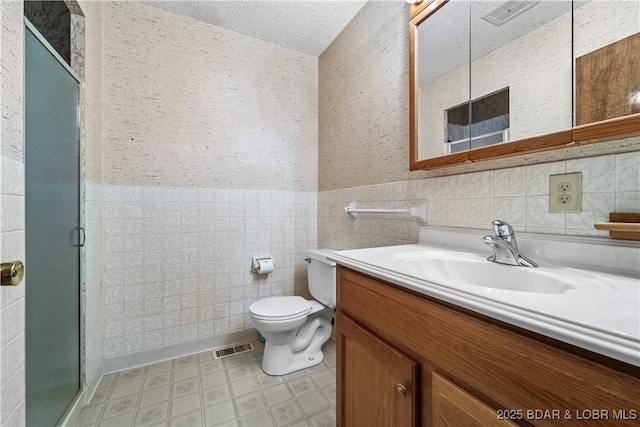 full bath featuring toilet, a shower stall, a textured ceiling, and vanity