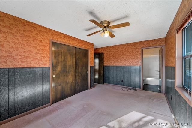 unfurnished bedroom featuring carpet floors, wallpapered walls, a closet, and a textured ceiling