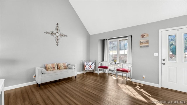 living area with high vaulted ceiling, baseboards, and wood finished floors