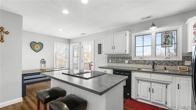 kitchen featuring dark countertops, black appliances, tasteful backsplash, and a sink