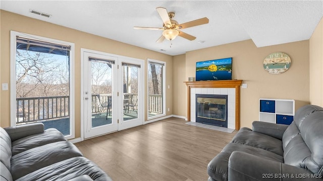5317 Locust Ct, Osage Beach, MO 65065 - living room with ceiling fan, wood finished floors, a tile fireplace, baseboards, and a textured ceiling