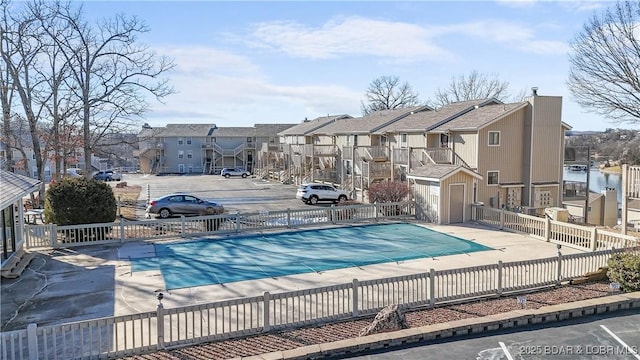 pool featuring a patio, fence, and a residential view