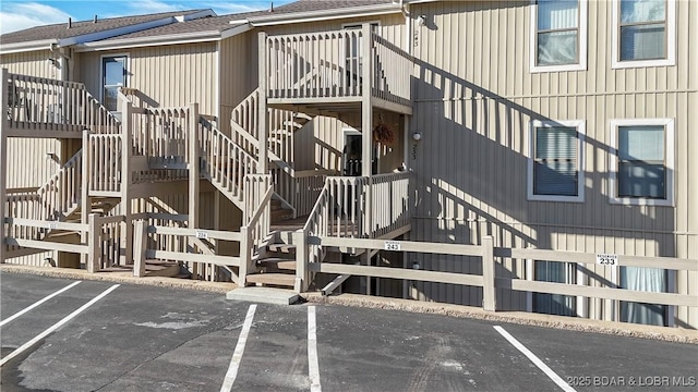 view of building exterior with uncovered parking and stairway