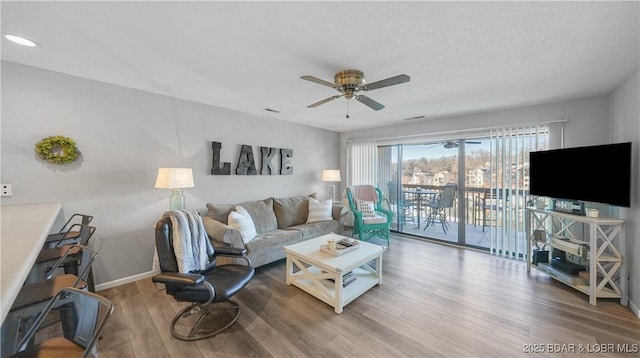 living room featuring ceiling fan, a textured ceiling, wood finished floors, and baseboards