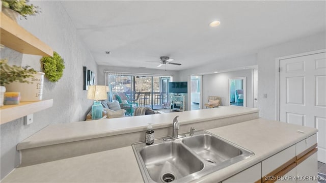 kitchen featuring recessed lighting, light countertops, a ceiling fan, open floor plan, and a sink