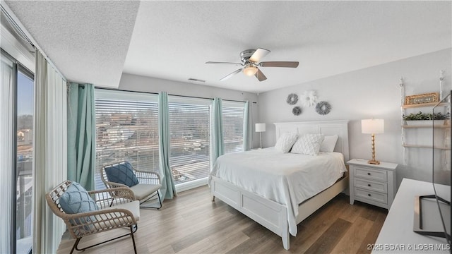 bedroom featuring a textured ceiling, access to outside, dark wood-style flooring, and a ceiling fan