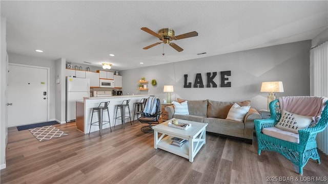 living area featuring a ceiling fan, recessed lighting, and wood finished floors