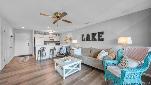 living room with light wood-style floors, ceiling fan, visible vents, and recessed lighting