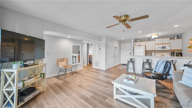 living area featuring baseboards, recessed lighting, a ceiling fan, and light wood-style floors