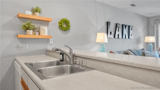 kitchen with white dishwasher, a sink, visible vents, light countertops, and open shelves