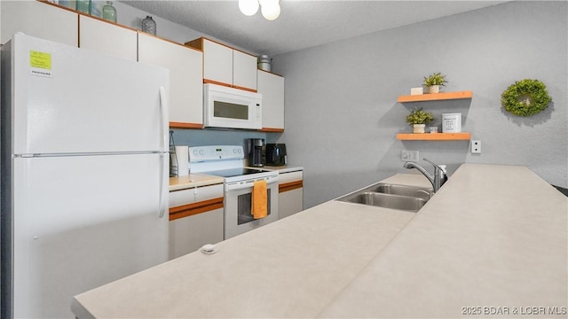 kitchen featuring open shelves, light countertops, white cabinetry, a sink, and white appliances