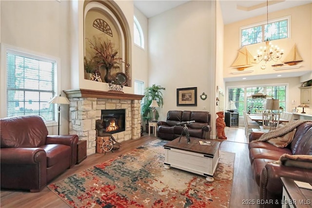 living area with an inviting chandelier, plenty of natural light, a fireplace, and wood finished floors