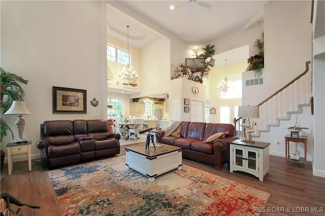 living room featuring baseboards, stairs, visible vents, and wood finished floors