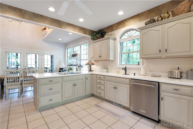 kitchen with a sink, a peninsula, stainless steel dishwasher, and light tile patterned floors