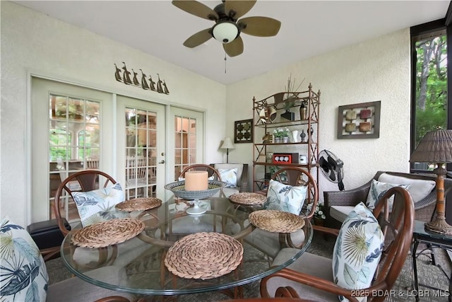 dining area with a textured wall, a ceiling fan, a wealth of natural light, and french doors