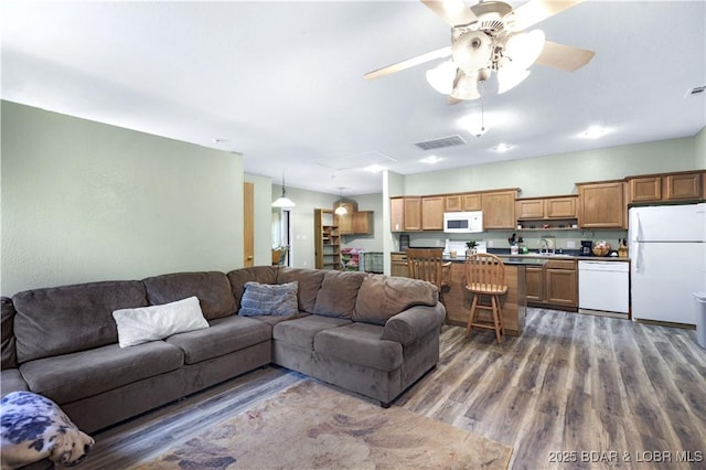 living area with ceiling fan, visible vents, and wood finished floors