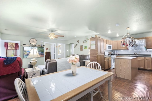 dining space featuring dark wood-style flooring and ceiling fan with notable chandelier