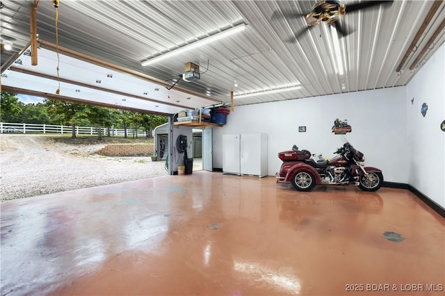 garage with a garage door opener, freestanding refrigerator, and baseboards