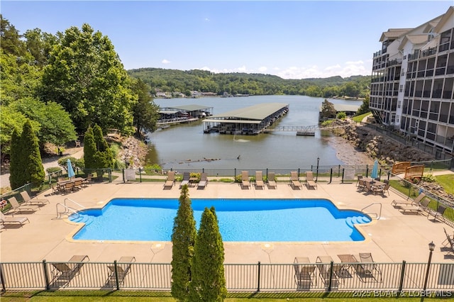 pool with a water view, fence, and a patio