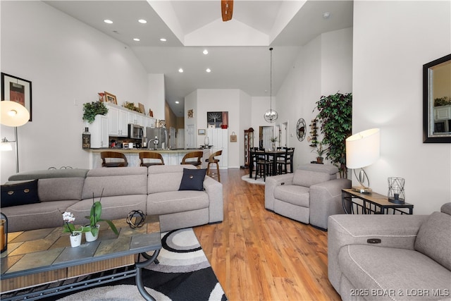 living area featuring light wood-style flooring, high vaulted ceiling, and recessed lighting