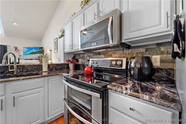 kitchen featuring white cabinets, dark stone counters, appliances with stainless steel finishes, a sink, and backsplash