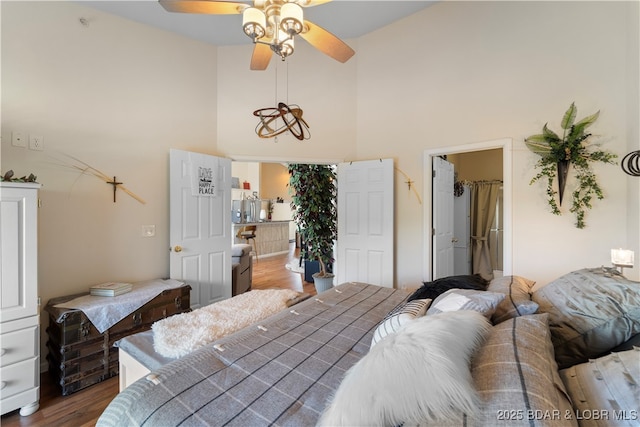 bedroom with wood finished floors, a towering ceiling, and a ceiling fan