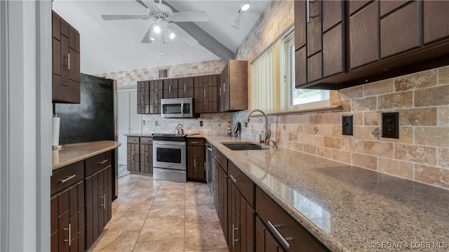 kitchen featuring light stone countertops, a sink, ceiling fan, stainless steel appliances, and backsplash