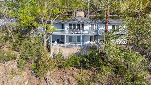 rear view of property with a chimney and a balcony