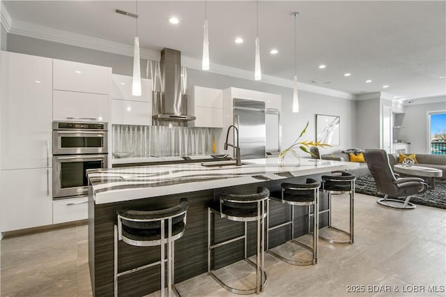 kitchen featuring modern cabinets, a sink, white cabinetry, appliances with stainless steel finishes, and wall chimney exhaust hood