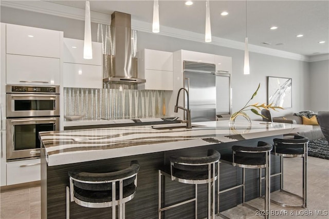 kitchen with a sink, appliances with stainless steel finishes, white cabinetry, wall chimney range hood, and modern cabinets