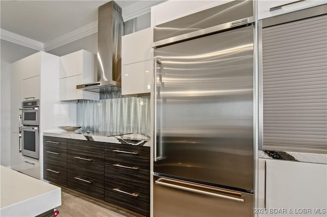 kitchen featuring white cabinetry, wall chimney range hood, modern cabinets, and appliances with stainless steel finishes