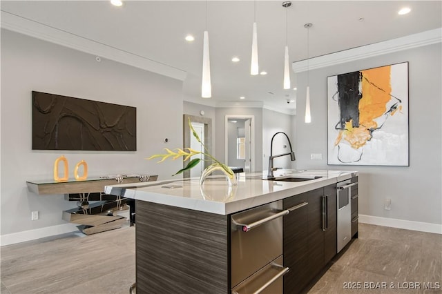 kitchen with ornamental molding, modern cabinets, an island with sink, and a sink