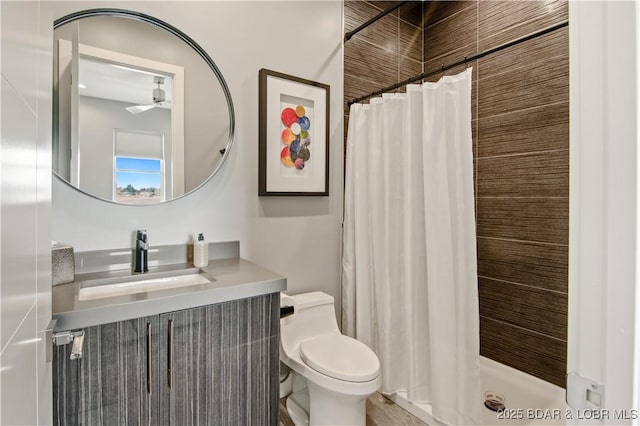 bathroom with vanity, toilet, ceiling fan, and a shower stall