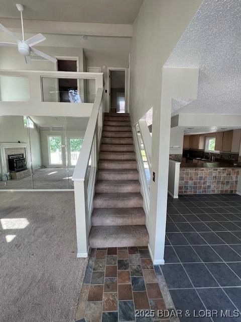 stairway featuring a textured ceiling, a wealth of natural light, a fireplace, and a towering ceiling