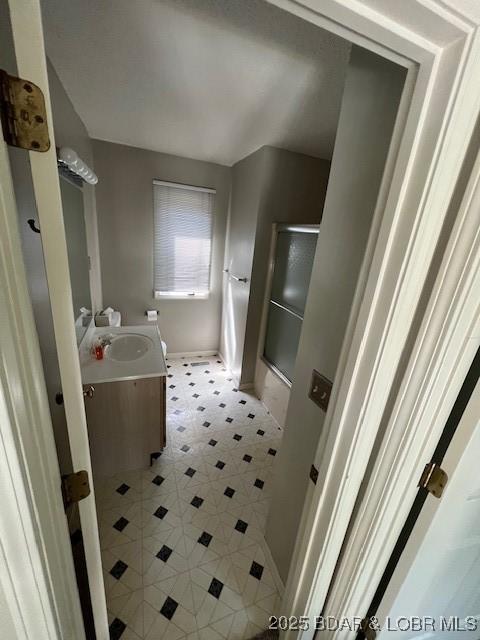 full bathroom featuring a tub, a shower with shower door, vanity, and baseboards