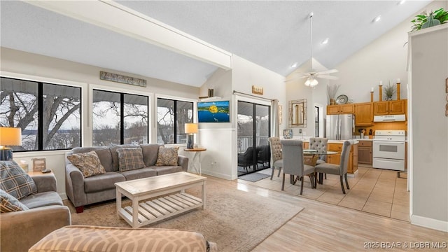 living area with recessed lighting, light wood-style floors, a ceiling fan, high vaulted ceiling, and baseboards