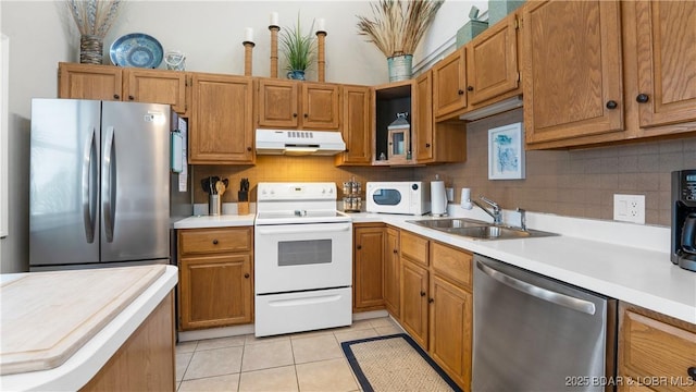 kitchen with light countertops, appliances with stainless steel finishes, a sink, and under cabinet range hood