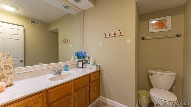 bathroom with toilet, visible vents, vanity, and baseboards