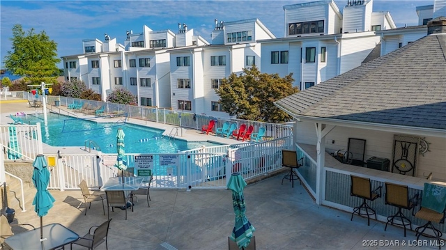 pool with a residential view, fence, and a patio