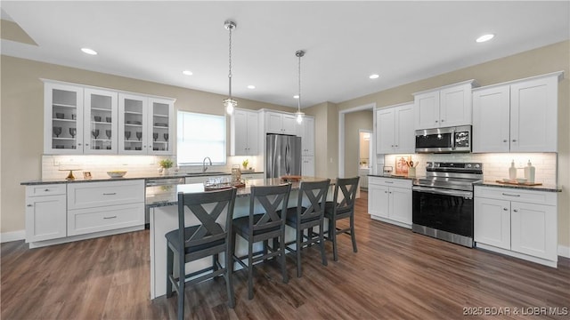 kitchen featuring appliances with stainless steel finishes, white cabinets, a sink, and a breakfast bar area