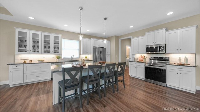 399 W End Cir, Osage Beach, MO 65065 - kitchen with stainless steel appliances, dark wood-type flooring, a kitchen breakfast bar, tasteful backsplash, and recessed lighting