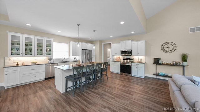 kitchen with a breakfast bar, stainless steel appliances, visible vents, open floor plan, and white cabinetry