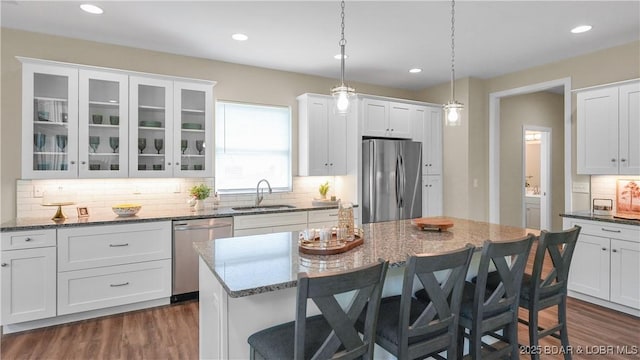 kitchen featuring a breakfast bar, a sink, white cabinetry, appliances with stainless steel finishes, and dark wood-style floors