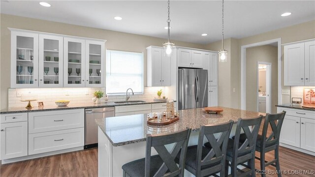 399 W End Cir, Osage Beach, MO 65065 - kitchen with appliances with stainless steel finishes, a breakfast bar, white cabinetry, backsplash, and glass insert cabinets