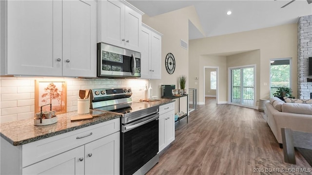 kitchen with tasteful backsplash, visible vents, dark stone counters, appliances with stainless steel finishes, and wood finished floors