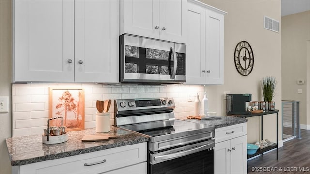 kitchen with visible vents, white cabinetry, appliances with stainless steel finishes, backsplash, and dark stone countertops