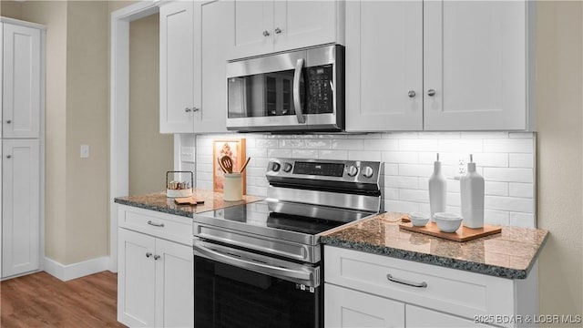 kitchen featuring appliances with stainless steel finishes, dark stone countertops, white cabinetry, and tasteful backsplash