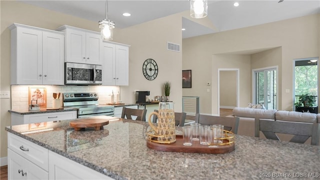 kitchen featuring visible vents, decorative backsplash, appliances with stainless steel finishes, white cabinetry, and light stone countertops